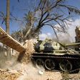Members of the self-styled Libyan National Army, loyal to the country's strongman Khalifa Haftar, roll a tank over a damaged building in central Benghazi on July 6, 2017