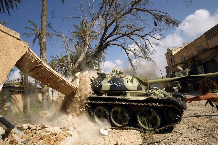 Members of the self-styled Libyan National Army, loyal to the country's strongman Khalifa Haftar, roll a tank over a damaged building in central Benghazi on July 6, 2017