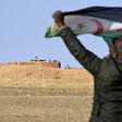 A Saharawi man holds up a Polisario Front flag in the Al-Mahbes area near Moroccan soldiers guarding the wall separating the Polisario controlled Western Sahara from Morocco on February 3, 2017