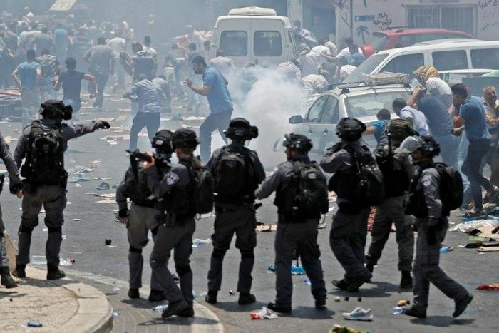 Palestinian worshippers run for cover as Israeli forces fire tear gas following protest prayers held outside Jerusalem's Old City on July 21, 2017, after police denied entry to men under 50