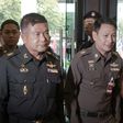 Thai Army Lieutenant General Manas Kongpan (C) surrounded by police officers when he turned himself in at the police headquarters in Bangkok