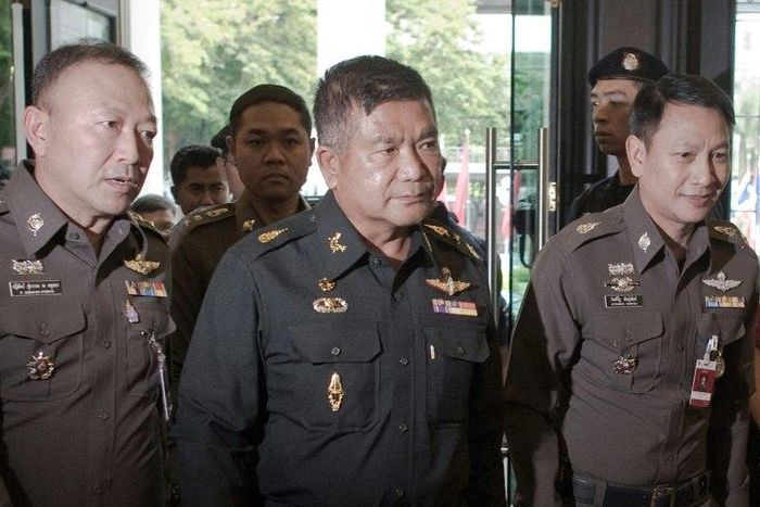 Thai Army Lieutenant General Manas Kongpan (C) surrounded by police officers when he turned himself in at the police headquarters in Bangkok