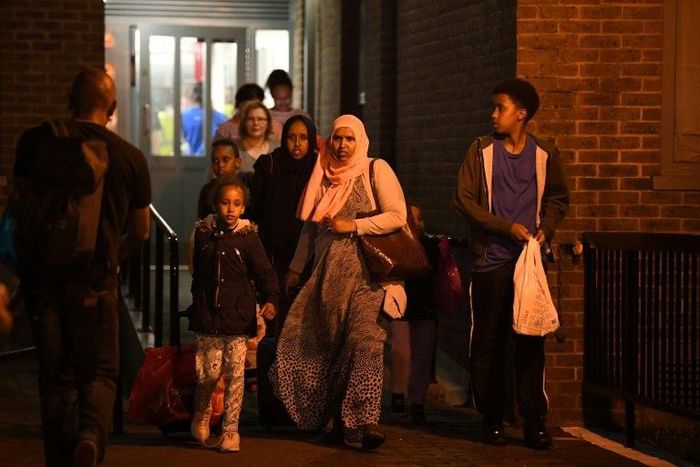 A family leave the Taplow Tower residential block on the Chalcots Estate in north London on June 23, 2017 as residents are evacuated because of fire safety concerns