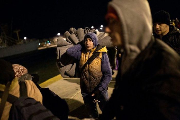Refugees and migrants disembark from a passenger ferry, with many presenting registration papers stating that Germany or Austria is their final destination, on January 23, 2016