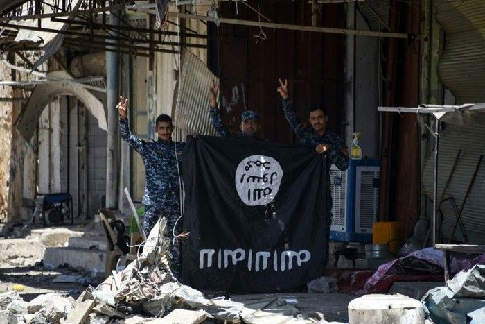 Iraqi government forces flash victory signs on June 9, 2017 while holding an Islamic State group flag in an area of western Mosul retaken from the jihadists