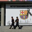 Armed Catalan policemen pass by the FC Barcelona logo with a black ribbon and a message reading, "We are all Barcelona" at the Camp Nou stadium in Barcelona on August 20, 2017