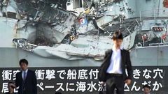 News of the collision between a US warship and a container vessel plays on a huge video screen as a probe into the cause of the crash was under way