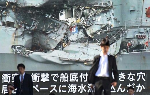News of the collision between a US warship and a container vessel plays on a huge video screen as a probe into the cause of the crash was under way