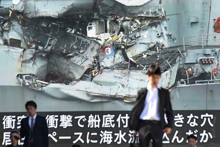 News of the collision between a US warship and a container vessel plays on a huge video screen as a probe into the cause of the crash was under way