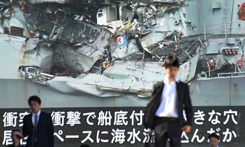 News of the collision between a US warship and a container vessel plays on a huge video screen as a probe into the cause of the crash was under way
