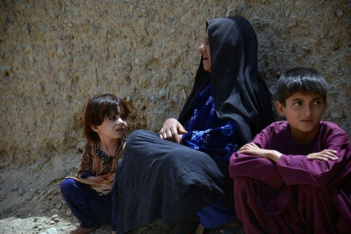 An internally-displaced Afghan woman and children who left their homes following a mass-kidnapping by suspected militants look on after arriving from the district of Shawali Kowt following in Kandahar on July 23, 2017
