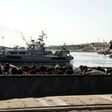 A Libyan coastguard watches on as illegal immigrants are brought to shore in a dinghy during a rescue on June 27, 2017