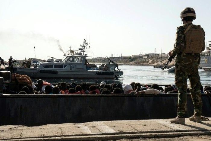 A Libyan coastguard watches on as illegal immigrants are brought to shore in a dinghy during a rescue on June 27, 2017