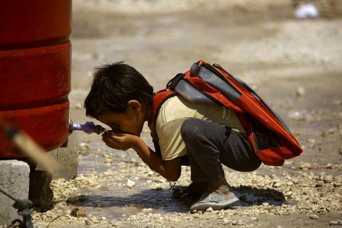 A Syrian child who has fled the Islamic State group's stronghold of Raqa, drinks water at a camp for internally displaced people in Ain Issa