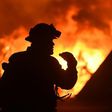A firefighter drinks water in front of a burning house near Oroville, California on July 9, 2017. Crews are battling the season's first major wildfires since the state's five-year drought ended earlier this year