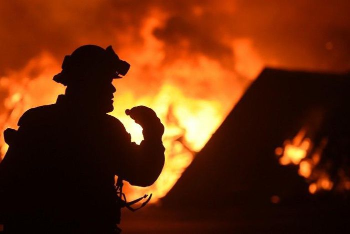 A firefighter drinks water in front of a burning house near Oroville, California on July 9, 2017. Crews are battling the season's first major wildfires since the state's five-year drought ended earlier this year
