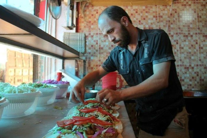 A Syrian man prepares food at the Ibad al-Rahman's Damascene Delicacies in the rebel-controlled northern city of Idlib on July 19
