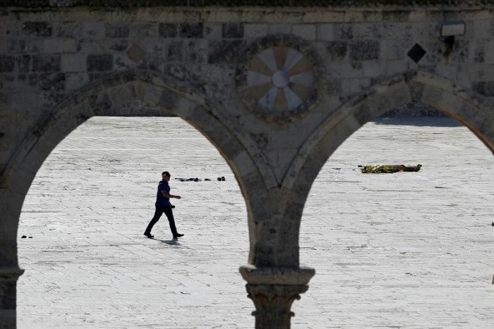 An Israeli policeman walks past a body at the Al-Aqsa mosque compound following an attack on security forces in Jerusalem's Old City on July 14, 2017
