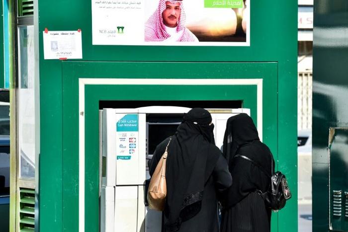 Saudi women withdraw money from an automatic teller machine along a main street in the capital Riyadh on December 18, 2018