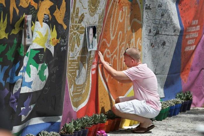 A visitor writes a message on a makeshift memorial one year after a gunman killed 49 people and wounded 53 at a gay nightclub in Orlando, Florida.
