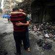 Iraqi men hug on July 4, 2016 at the site of a suicide-bombing attack which took place in Baghdad's Karrada neighbourhood
