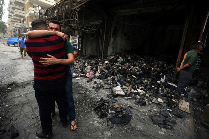 Iraqi men hug on July 4, 2016 at the site of a suicide-bombing attack which took place in Baghdad's Karrada neighbourhood