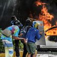 Anti-government demonstrators take cover behind shields near a burning car during clashes near Altamira Square in Caracas, on June 14, 2017