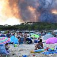 People watch from the beach as smoke billows into the sky over Bormes-les-Mimosas
