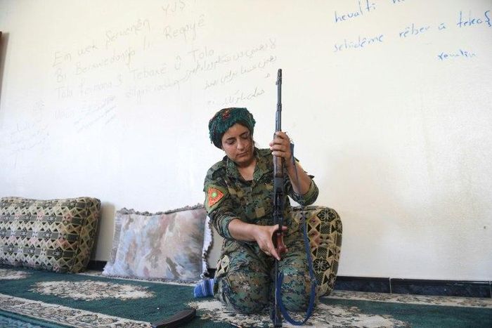 Yazidi fighter Heza prepares her rifle in an abandoned home used as a base on the eastern outskirts of Raqa on July 18, 2017