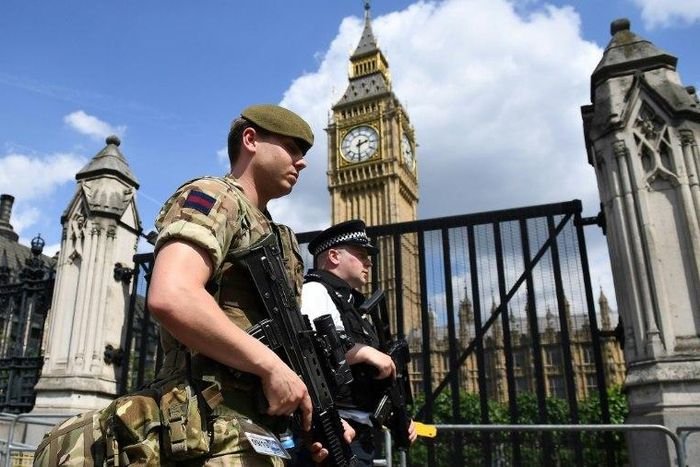 A British soldier and armed policeman patrol near the Houses of Parliament in central London