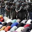 Israeli border guards keep watch as Palestinian worshippers pray outside Jerusalem's Old City overlooking the Al-Aqsa mosque compound on July 28, 2017