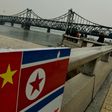 The Chinese and North Korean flags attached to a railing as trucks carrying Chinese-made goods cross into North Korea on the Sino-Korean Friendship Bridge at the Chinese border town of Dandong on December 18, 2013