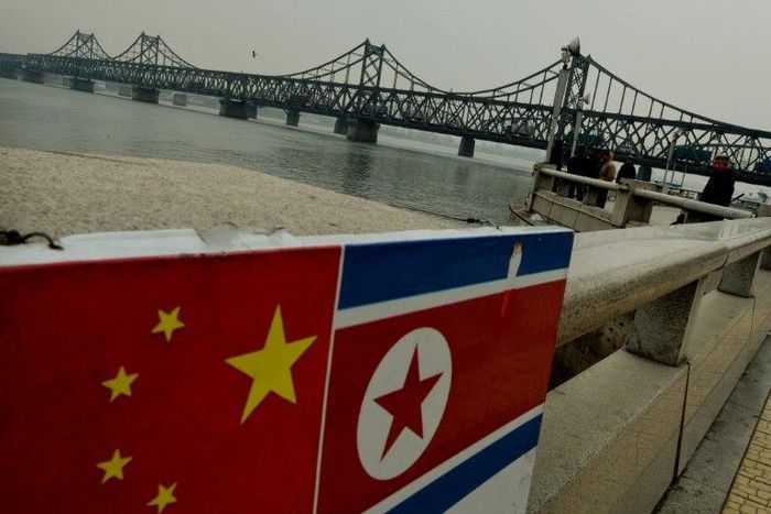 The Chinese and North Korean flags attached to a railing as trucks carrying Chinese-made goods cross into North Korea on the Sino-Korean Friendship Bridge at the Chinese border town of Dandong on December 18, 2013