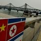 The Chinese and North Korean flags attached to a railing as trucks carrying Chinese-made goods cross into North Korea on the Sino-Korean Friendship Bridge at the Chinese border town of Dandong on December 18, 2013