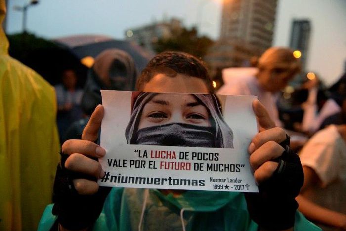 An opposition activist holds a sign reading "The fight of the few is for the future of the many" during a protest against Venezuelan President Nicolas Maduro in Caracas on July 13, 2017