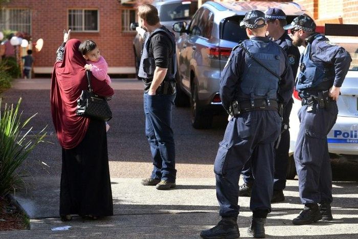 Police direct locals around a block of flats in the Sydney suburb of Lakemba after counter-terrorism raids across the city