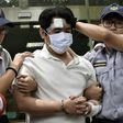 A man identified only by his family name Lu (C), is escorted by policemen after he was suspected of slashing a guard with a Samurai sword at Taiwan's Presidential Palace