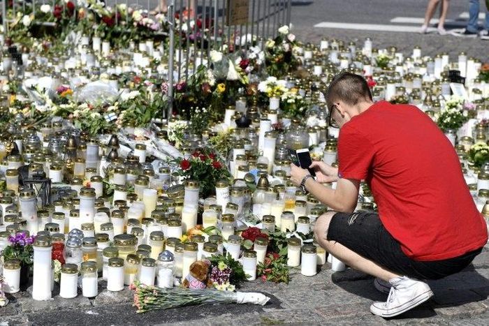 People bring candles and flowers to a makeshift memorial for the victims of the stabbings in the Finnish city of Turku