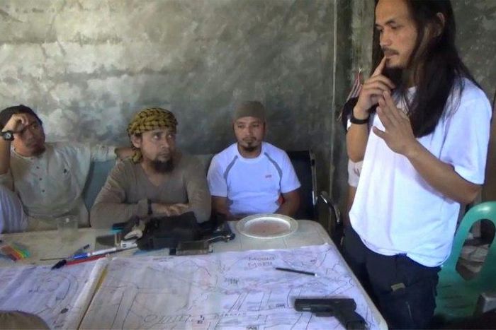 Screengrab taken from video released by the Philippine Army on June 18, 2017 shows Isnilon Hapilon (2nd L), leader of hardline group Abu Sayyaf, and Abdullah Maute (R) discussing an improvised map of Marawi at an undisclosed location on Mindanao