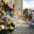 People look at floral tributes for victims of the Grenfell Tower block fire that have been left outside the Notting Hill Methodist Church in west London, on June 17, 2017