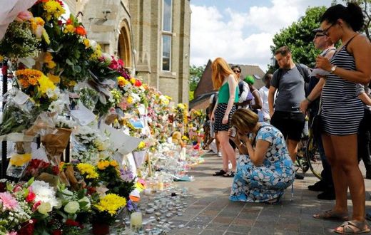 People look at floral tributes for victims of the Grenfell Tower block fire that have been left outside the Notting Hill Methodist Church in west London, on June 17, 2017