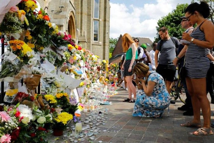 People look at floral tributes for victims of the Grenfell Tower block fire that have been left outside the Notting Hill Methodist Church in west London, on June 17, 2017