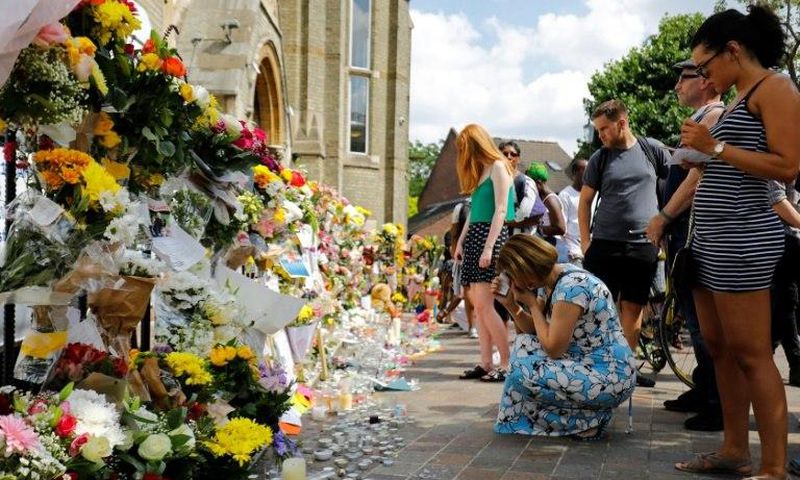 People look at floral tributes for victims of the Grenfell Tower block fire that have been left outside the Notting Hill Methodist Church in west London, on June 17, 2017