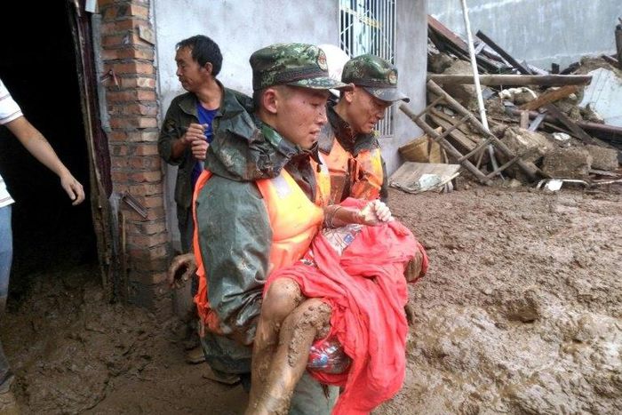 Rescuers carry a survivor of the landslide at Puge