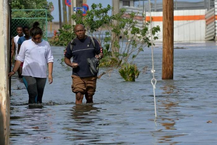 People wading through a flooded street in Havana, on December 21, 2018: Cuba blamed last year's Hurricane Irma as well as US sanctions for the fact that it won't be able to pay off its debt commitments in 2019