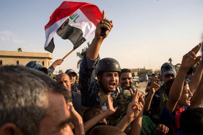 Members of Iraq's federal police force wave Iraq's national flag as they celebrate in the Old City of Mosul on July 9, 2017 after recapturing the city