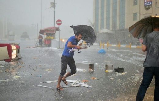 A man holds an umrella during a heavy downpour of hail at Taksim in Istanbul on July 27, 2017