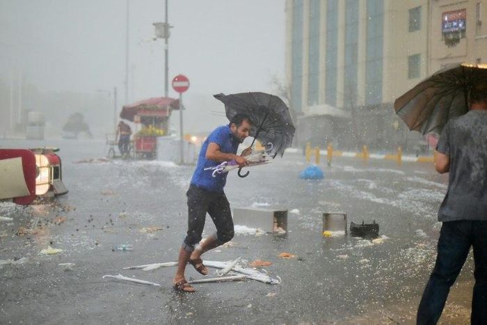 A man holds an umrella during a heavy downpour of hail at Taksim in Istanbul on July 27, 2017