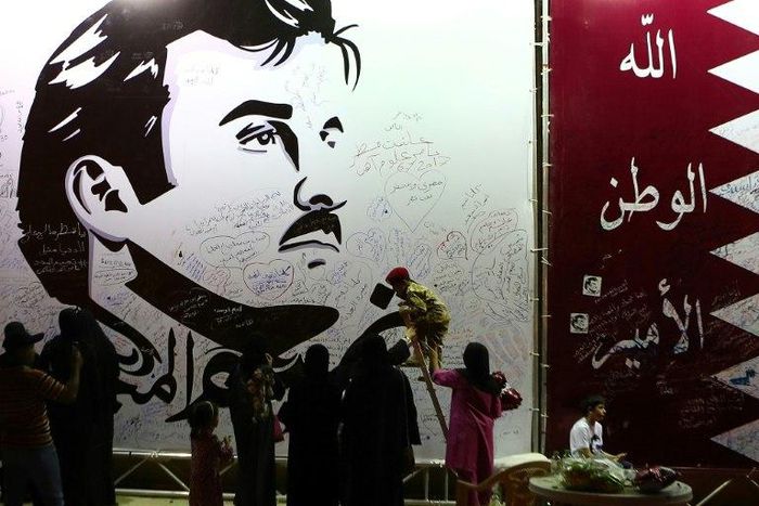 Qataris write comments on a wall bearing a portrait of Qatar's Emir, Sheikh Tamim bin Hamad Al Thani, which has become the symbol of Qatari resistance during the row between Doha and neighbouring countries, in Doha on July 6, 2017
