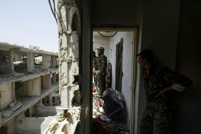 Members of the US-backed Syrian Democratic Forces move through destroyed buildings in Raqa on July 28, 2017